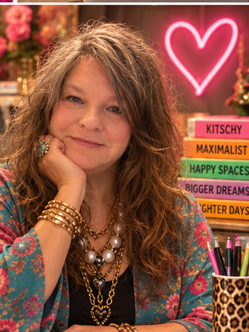 Stacie resting her chin on her hand with a stack of Kitschy Maximalist books and a neon heart behind her